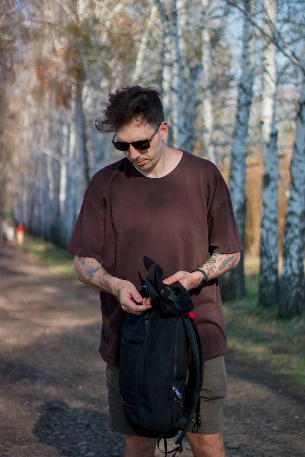 a man in a brown shirt is holding a black backpack