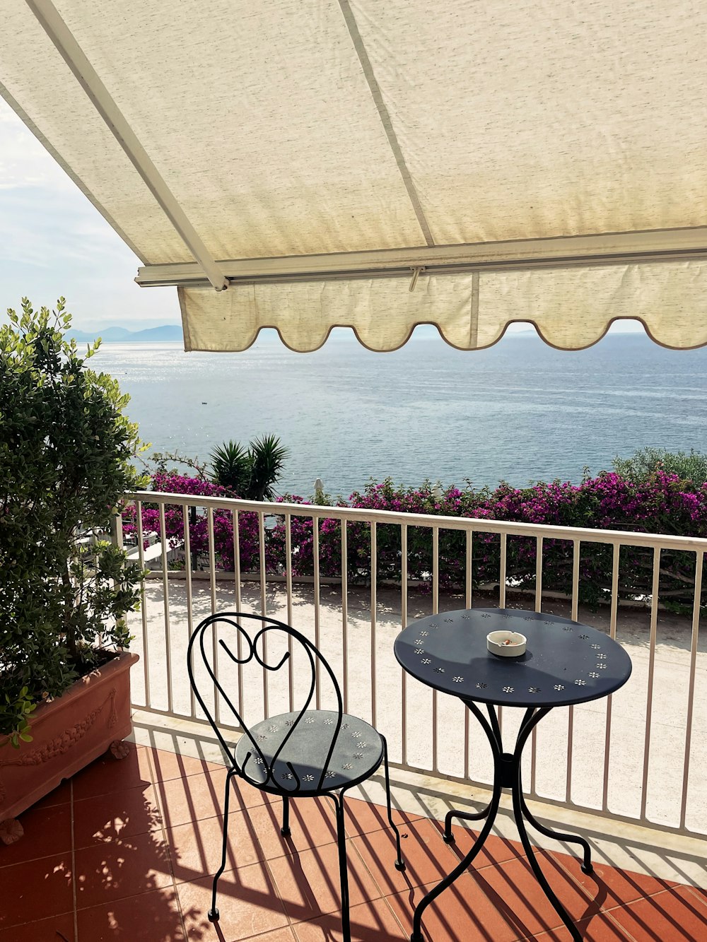 un balcon avec une table et des chaises et une vue sur l’océan