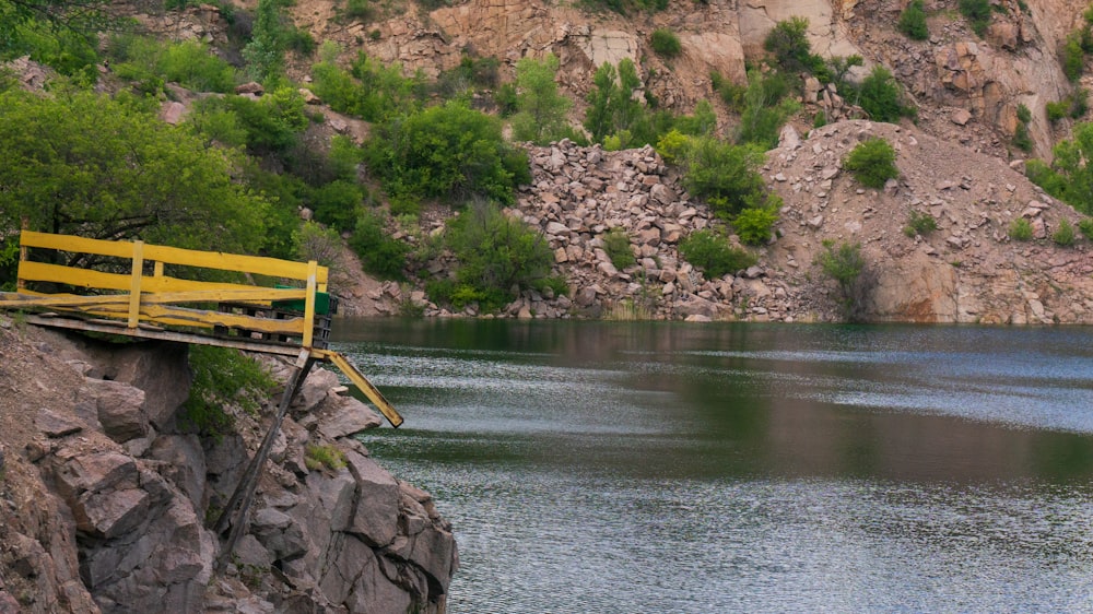 a yellow bench sitting on top of a cliff next to a body of water