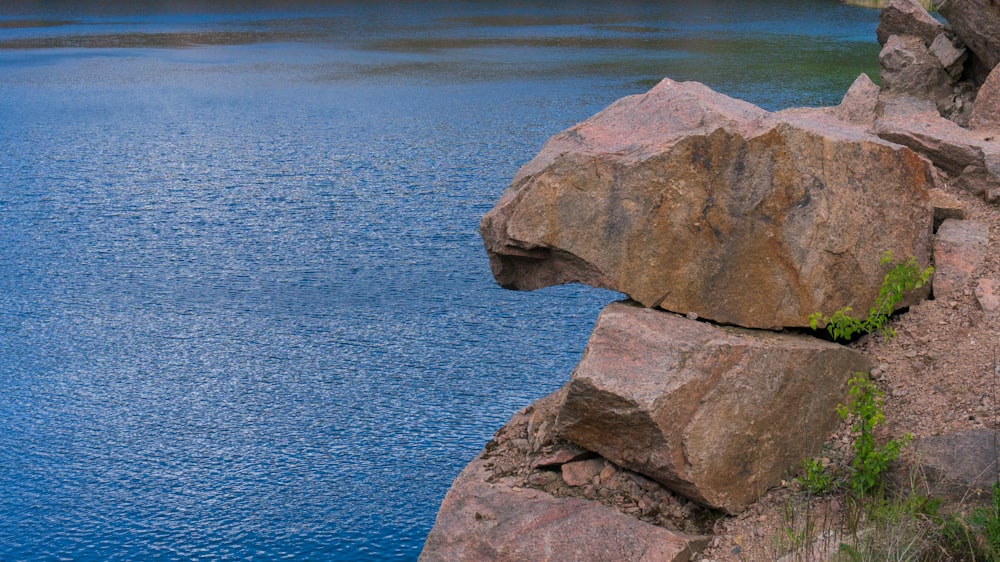 a large rock sitting on the side of a body of water
