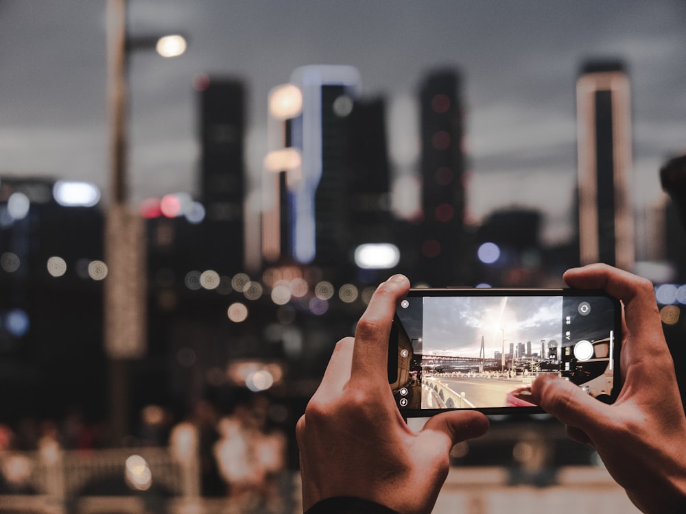 a person taking a picture of a city at night