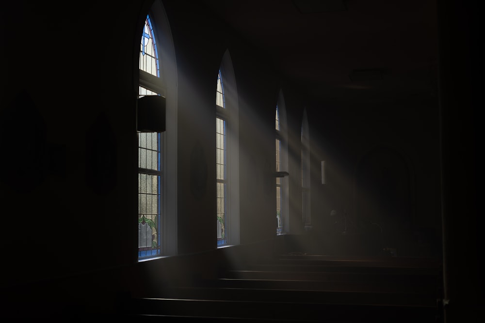 a dark room with sunlight streaming through the windows
