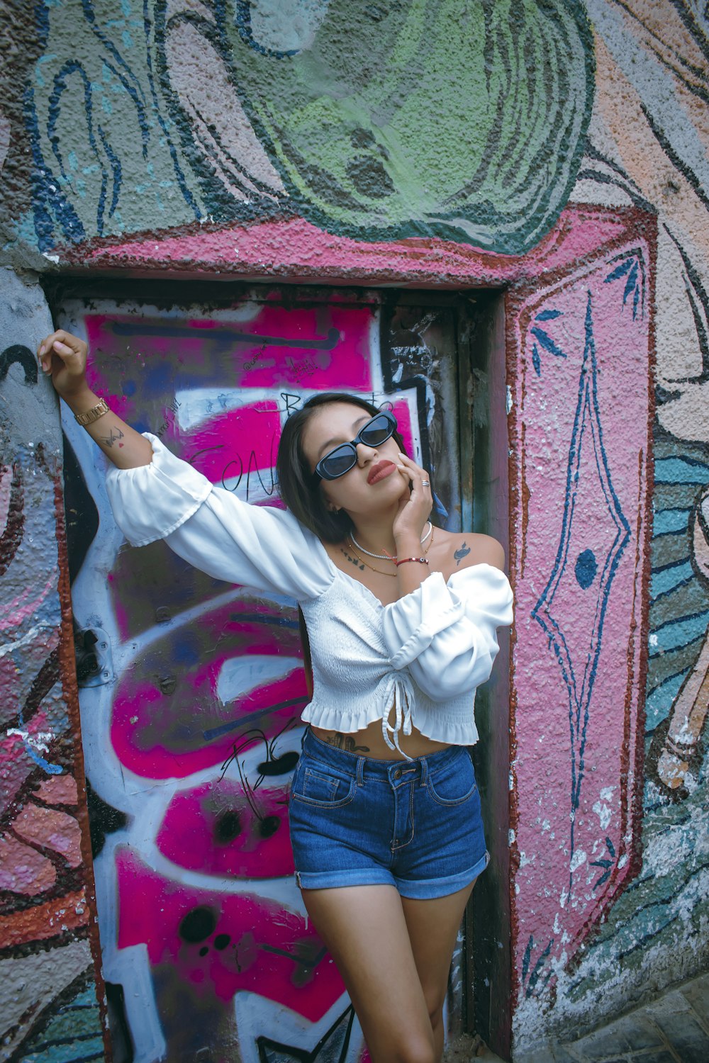 a woman standing in front of a wall covered in graffiti