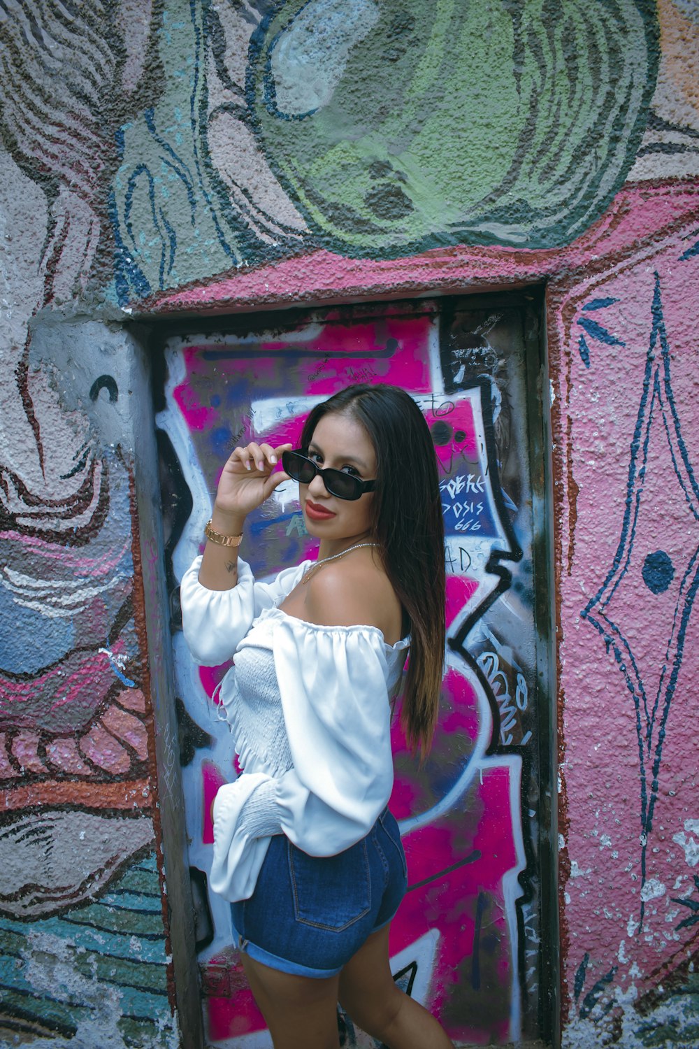 a woman standing in front of a graffiti covered wall