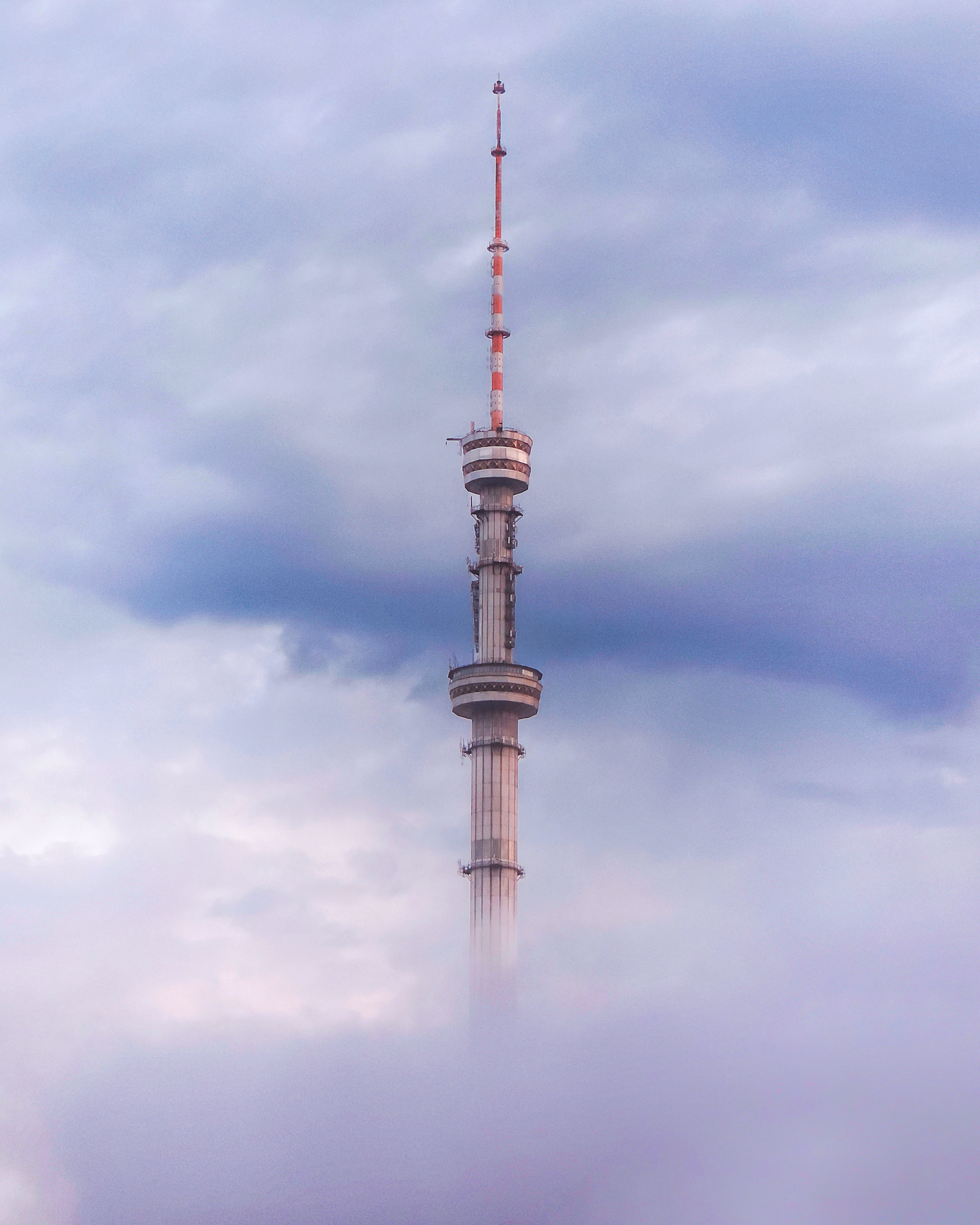 A telecommunications tower rising through low clouds above Almaty.