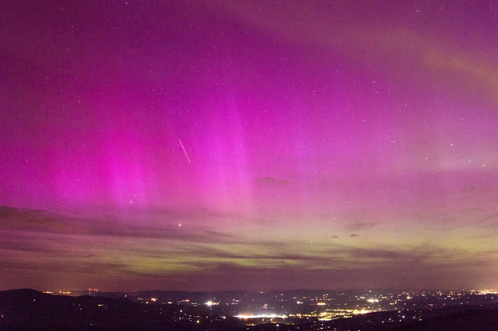 a bright purple and green aurora over a city