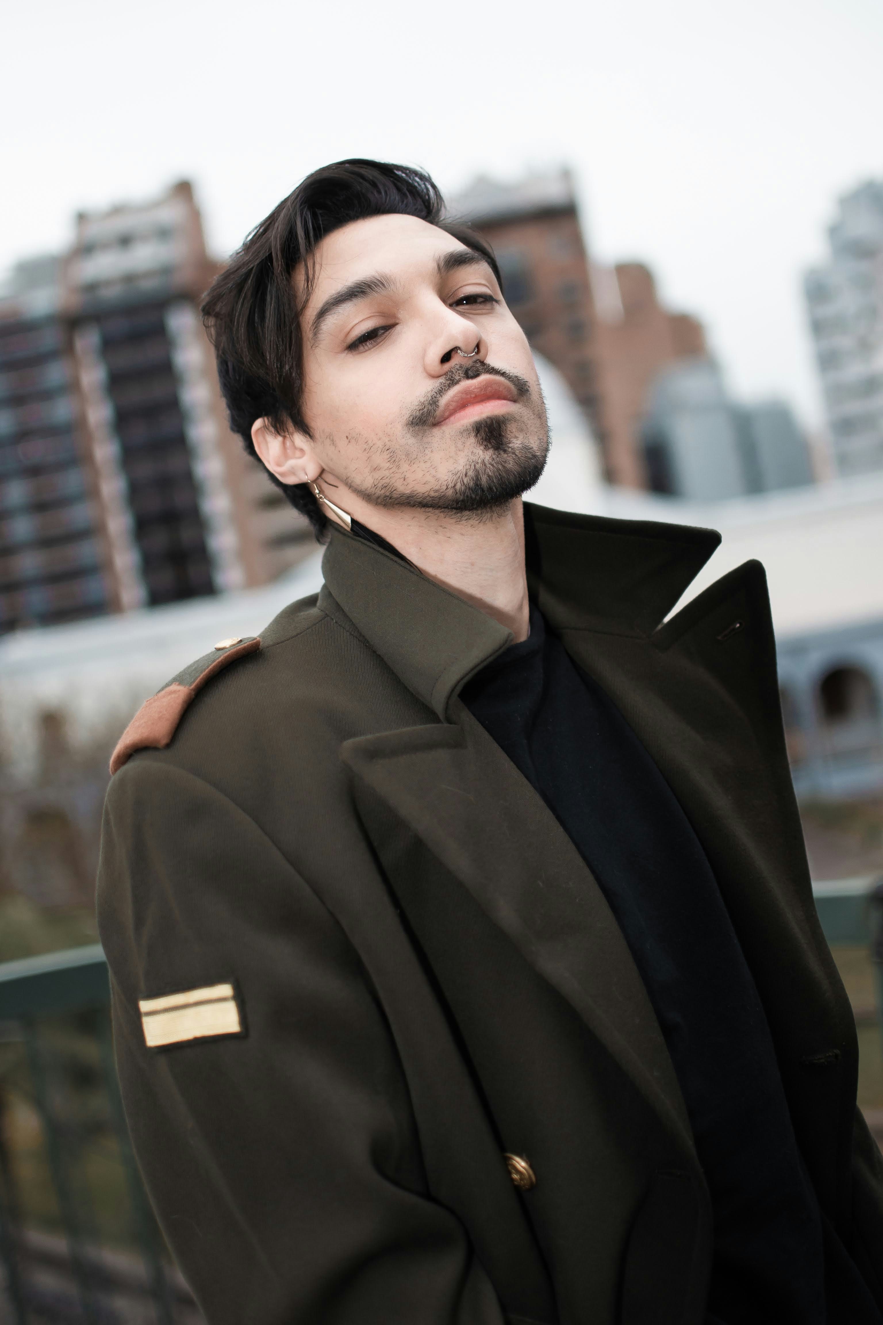 a man with his eyes closed standing in front of a fence