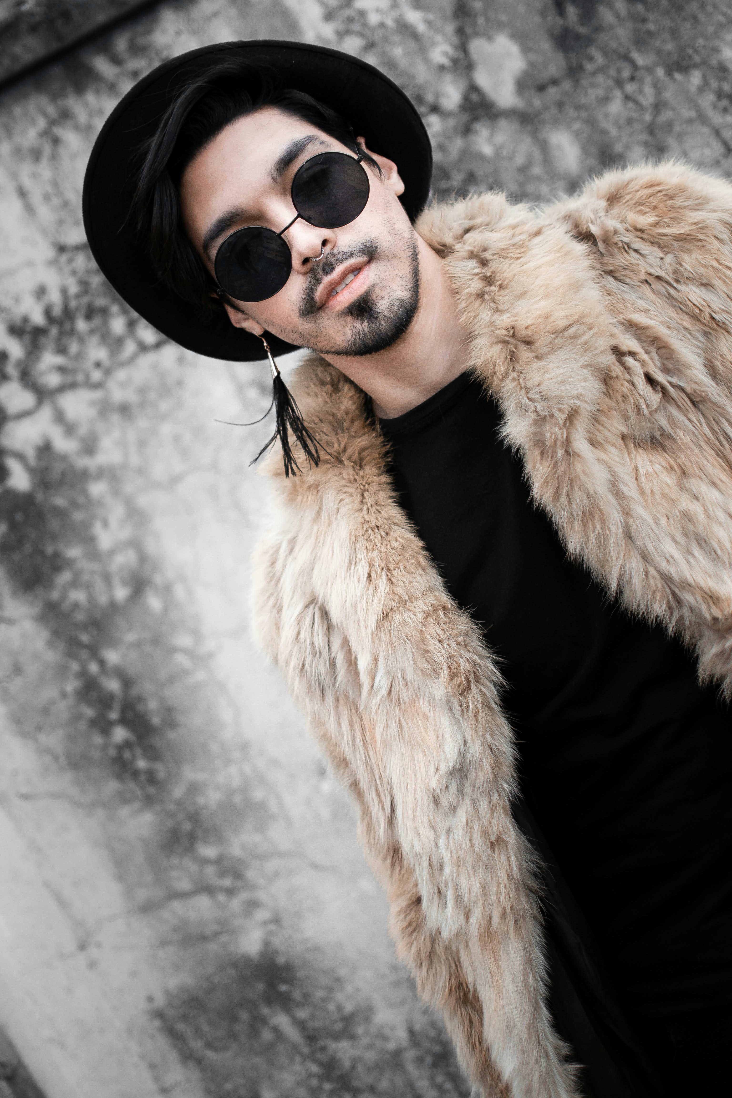 a man in a hat and sunglasses posing for a picture