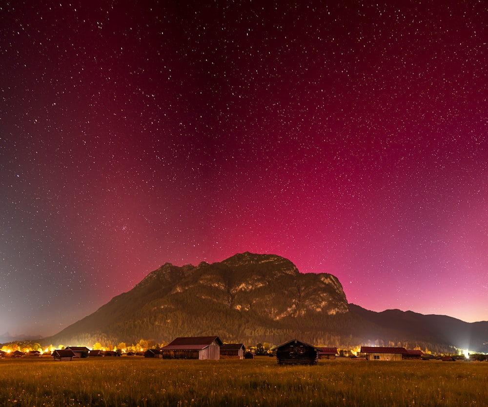 a field with a mountain in the background and stars in the sky
