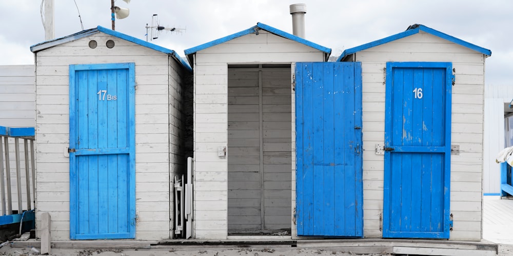 a group of blue and white beach huts sitting next to each other
