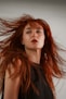 a woman with red hair blowing in the wind