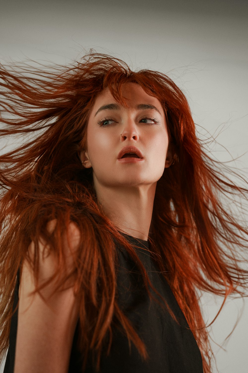 a woman with red hair blowing in the wind
