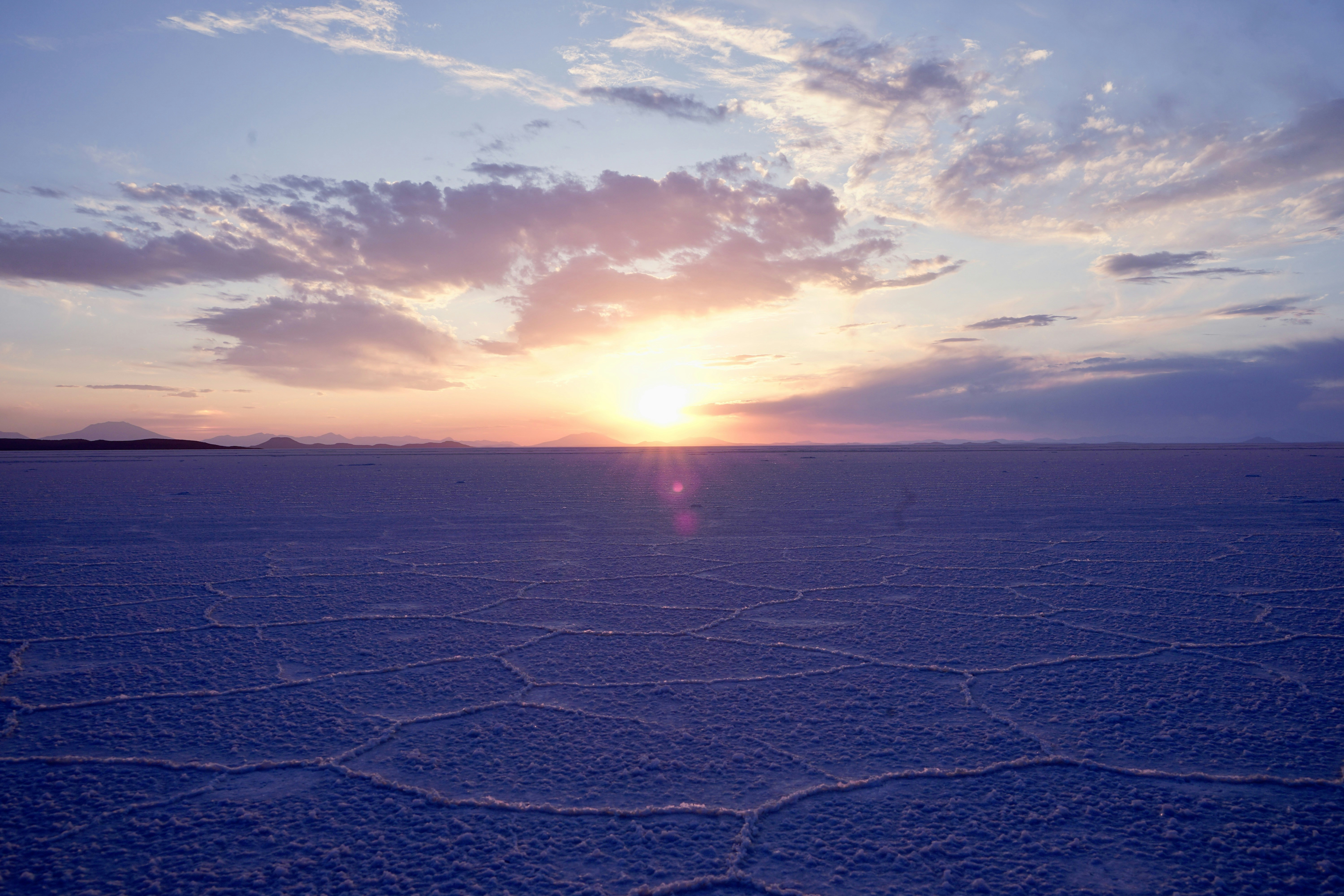 the sun is setting over a vast expanse of flat land, 