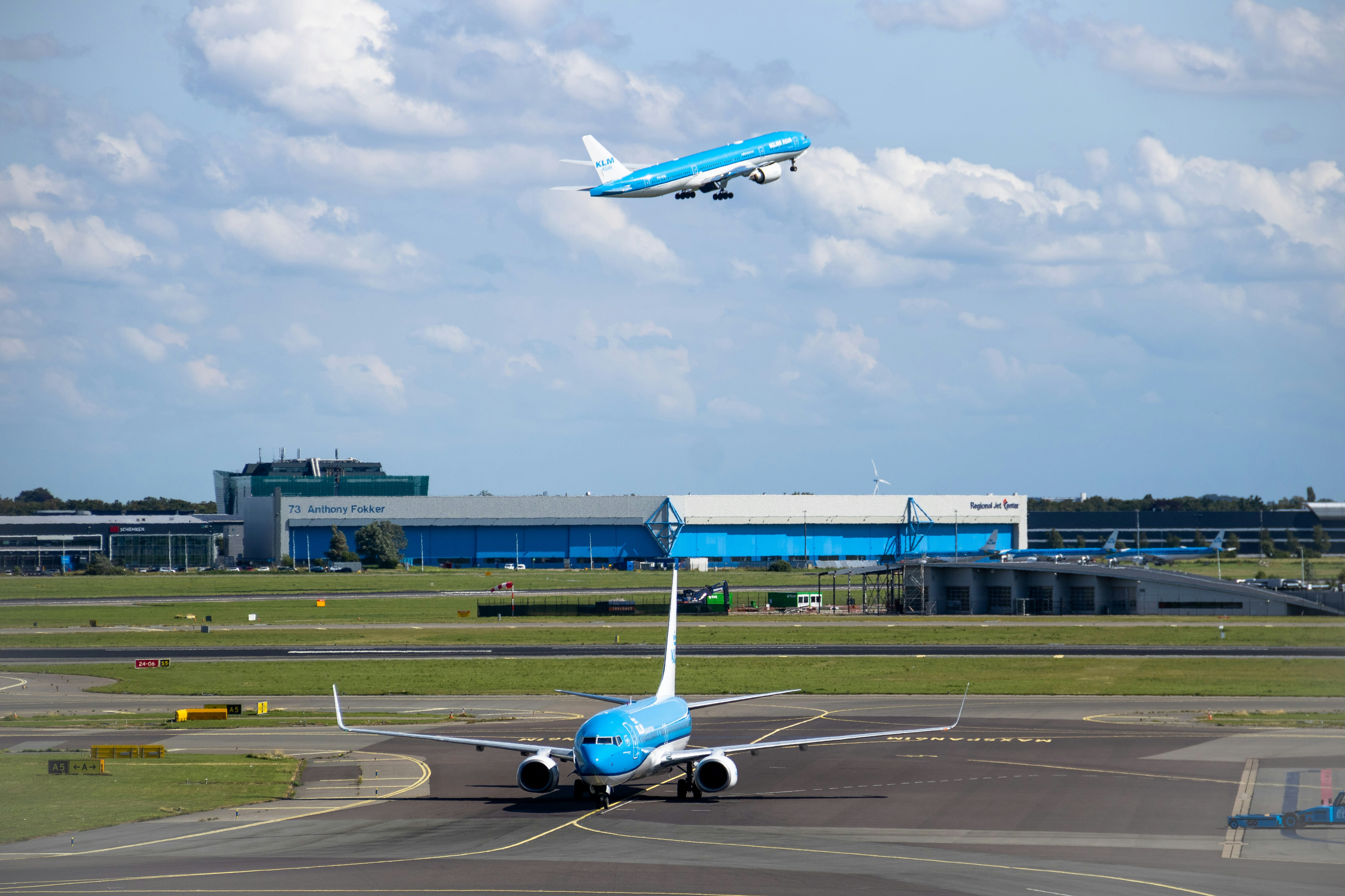 a blue and white jet airliner taking off from an airport runway