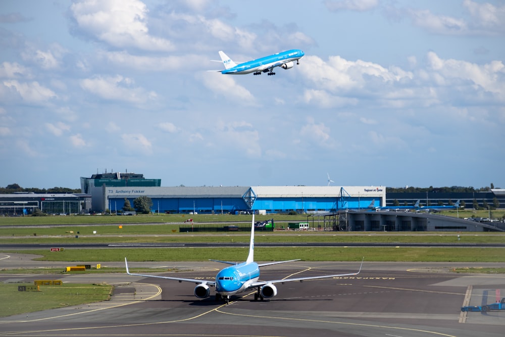 a blue and white jet airliner taking off from an airport runway