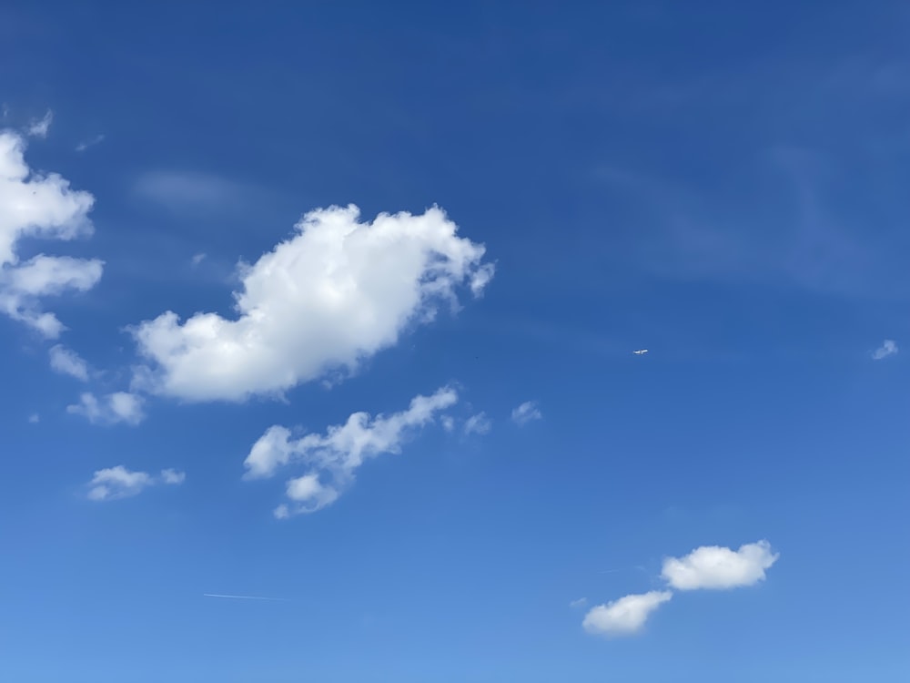 a plane flying in a blue sky with clouds