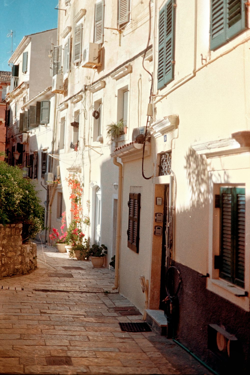 a narrow street lined with white buildings and green shutters