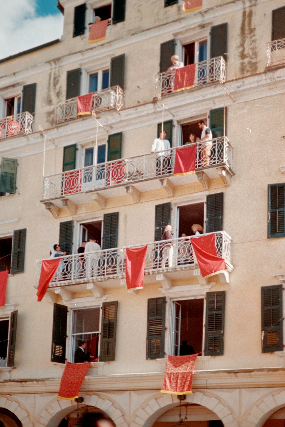 a tall building with balconies and red flags hanging from the balconies