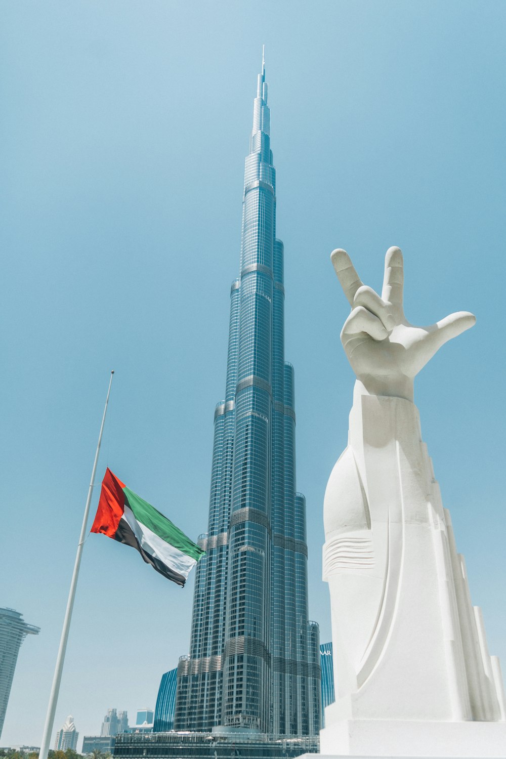 a statue of a hand and a flag in front of a tall building