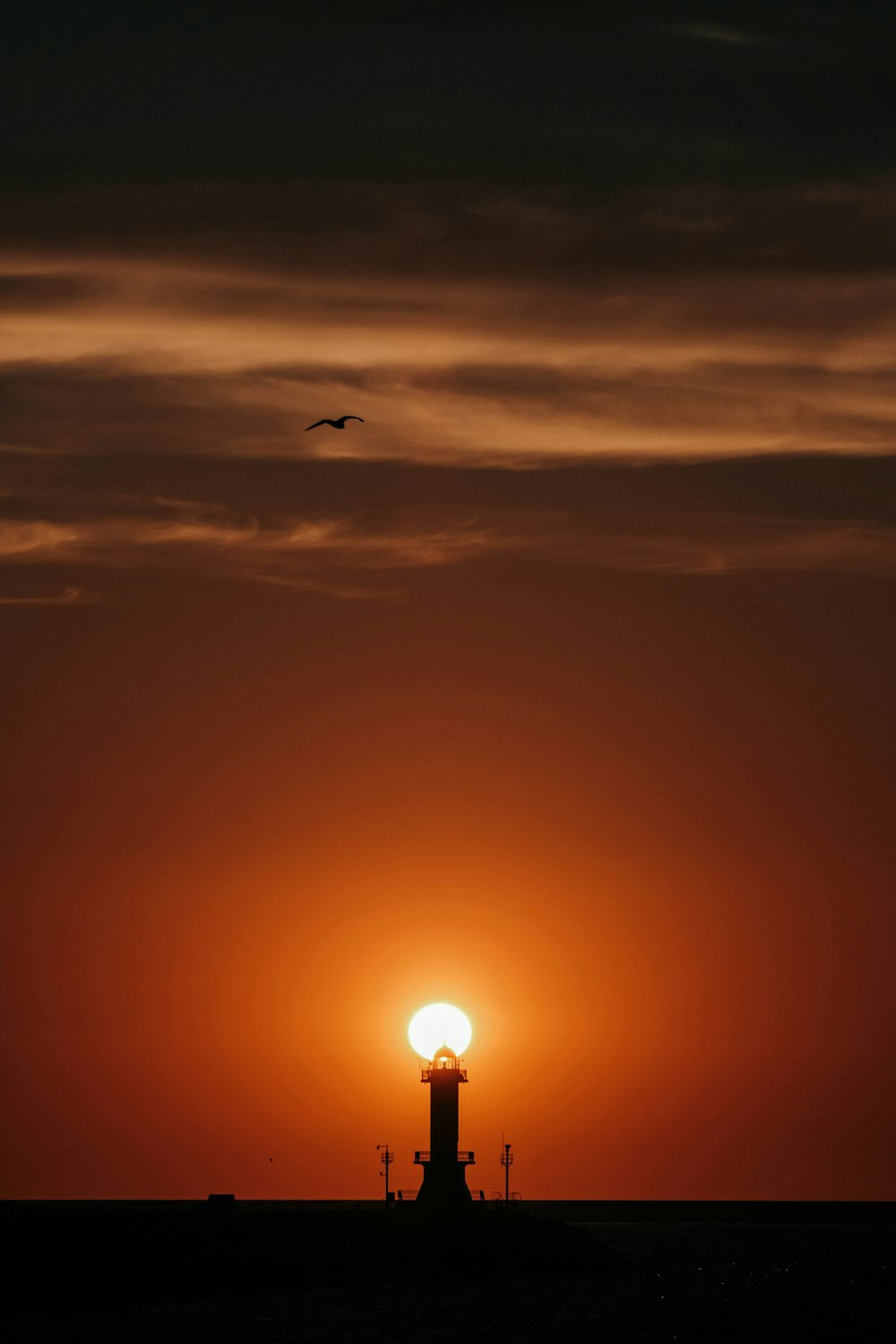 le soleil se couche derrière un phare ;