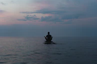 a man sitting on a surfboard in the middle of the ocean