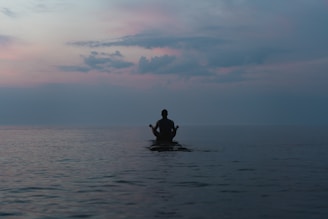 a man sitting on a surfboard in the middle of the ocean