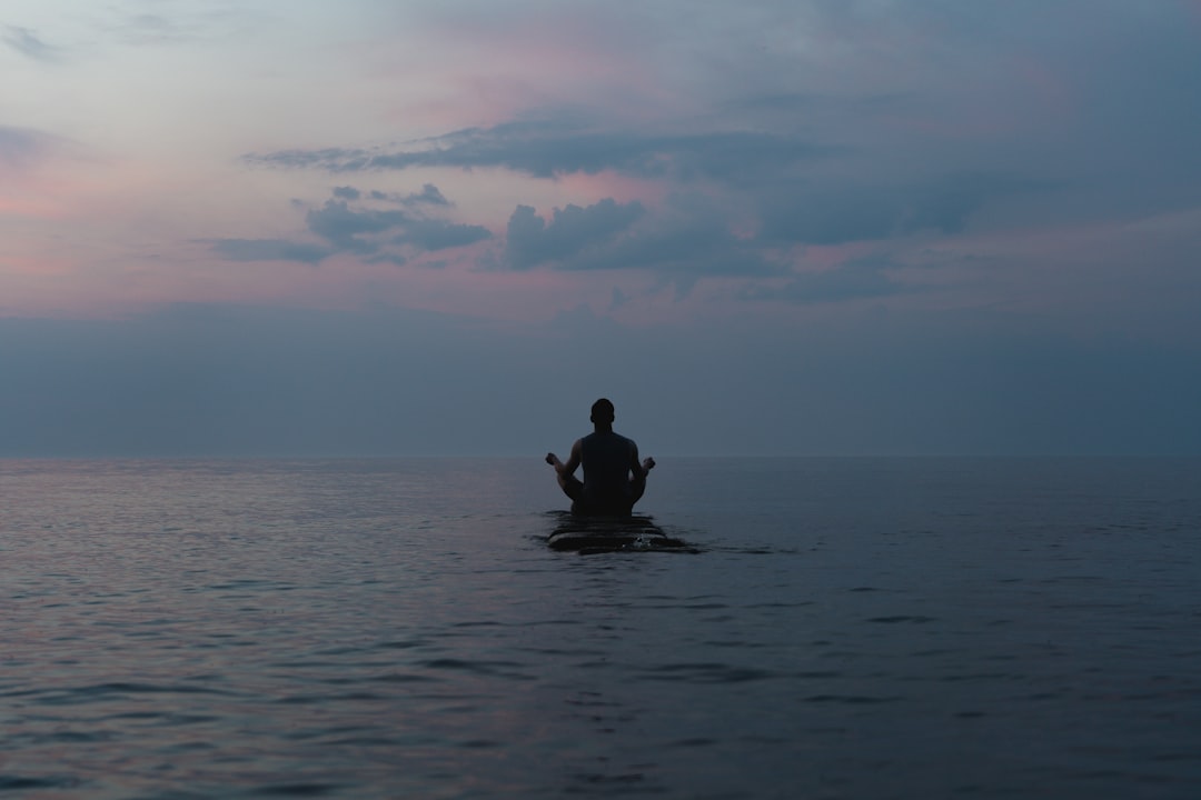 a man sitting on a surfboard in the middle of the ocean,