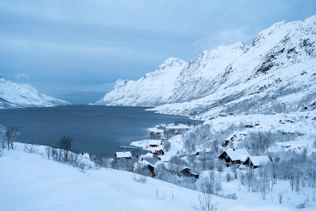 a snowy landscape with a lake and mountains in the background,