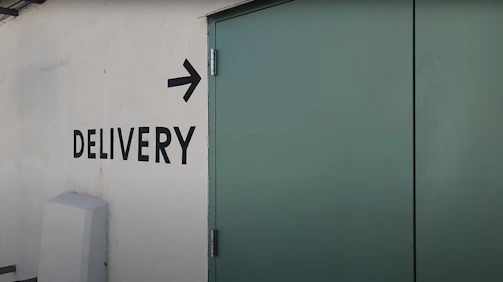 a sign on the side of a building that says delivery