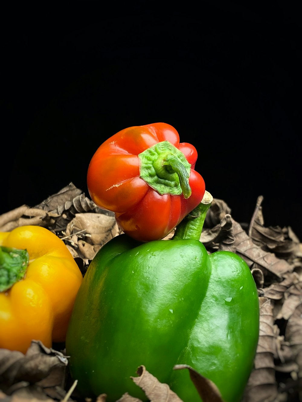 a group of peppers sitting on top of a pile of leaves
