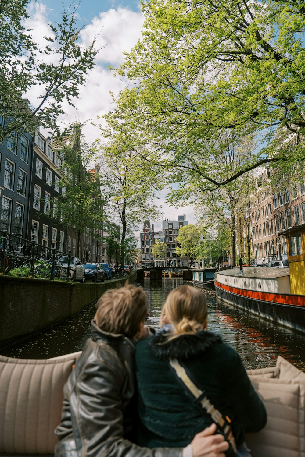 two people are sitting on a boat in a canal