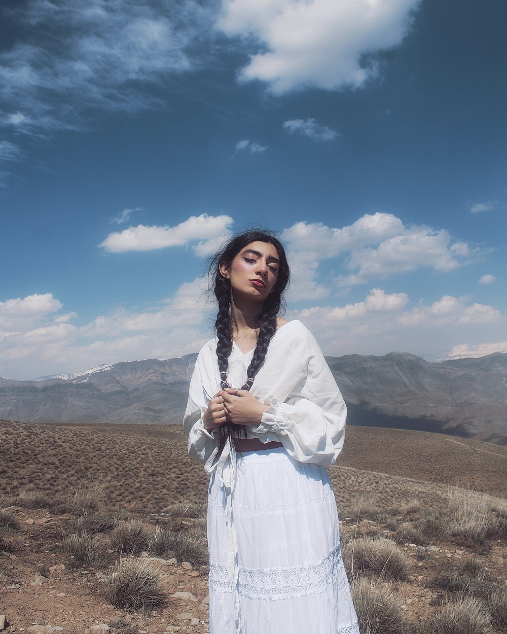 a woman in a white dress standing in the desert