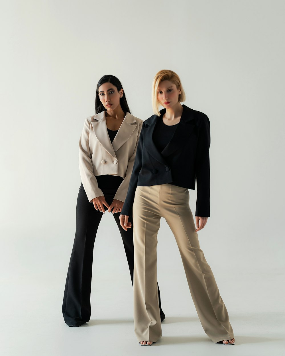 two women standing next to each other in front of a white background