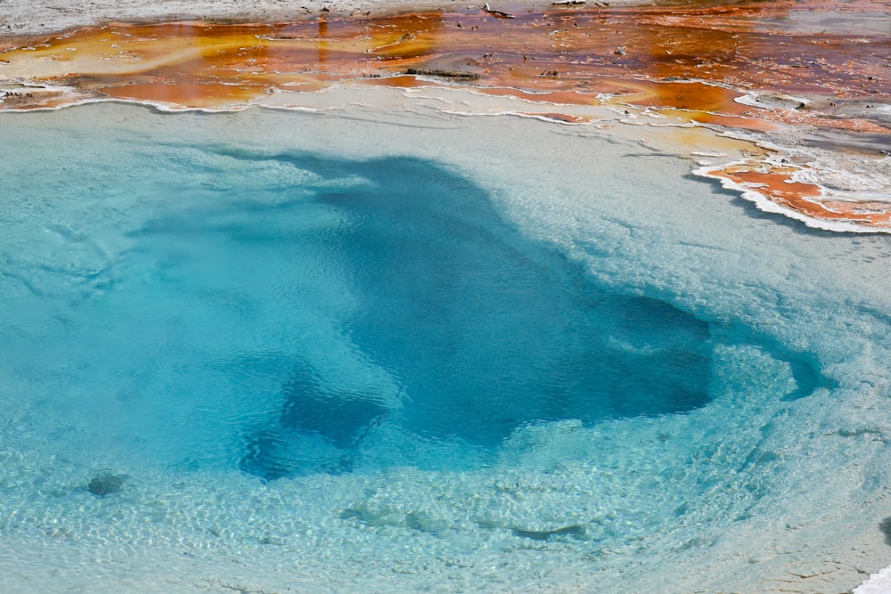 a blue pool of water surrounded by yellow and brown rocks