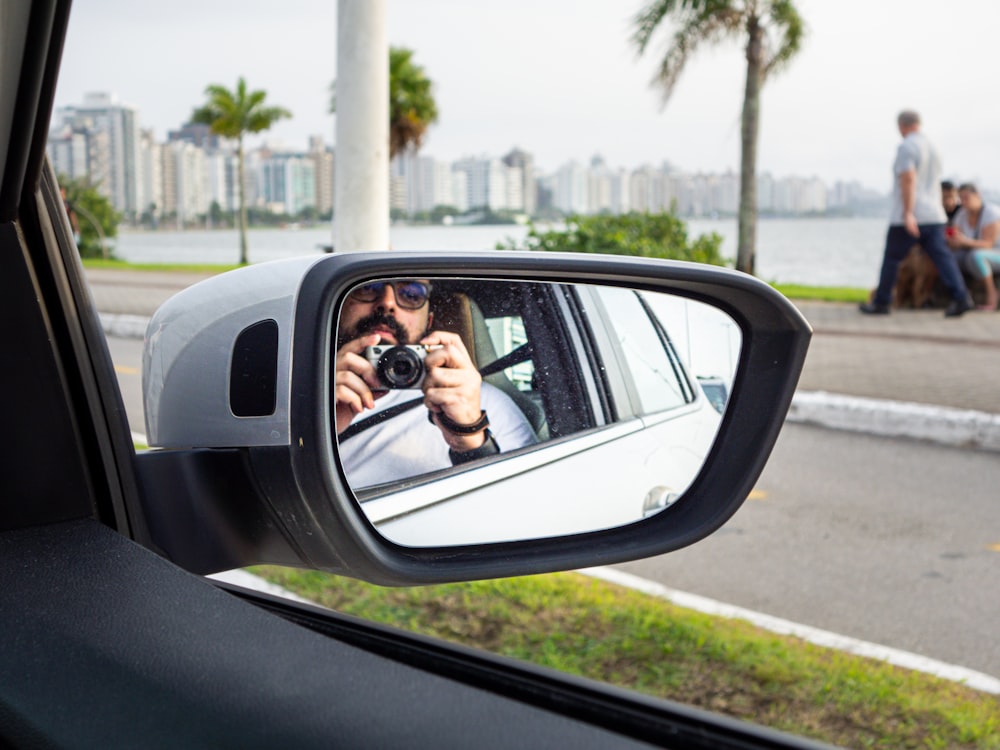 a man taking a picture of himself in a car mirror