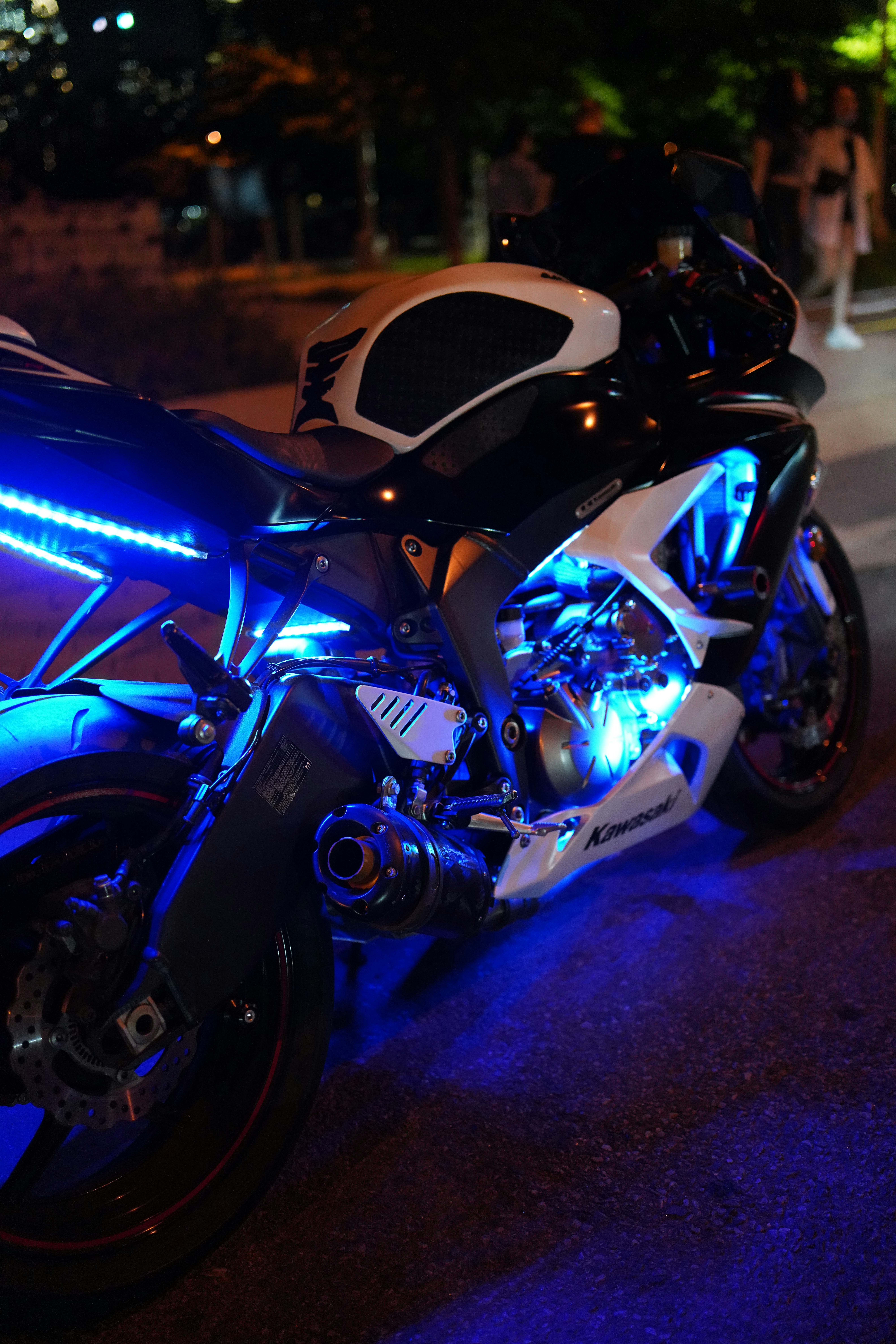 Futuristic black electric motorcycle with neon blue underglow on dark asphalt