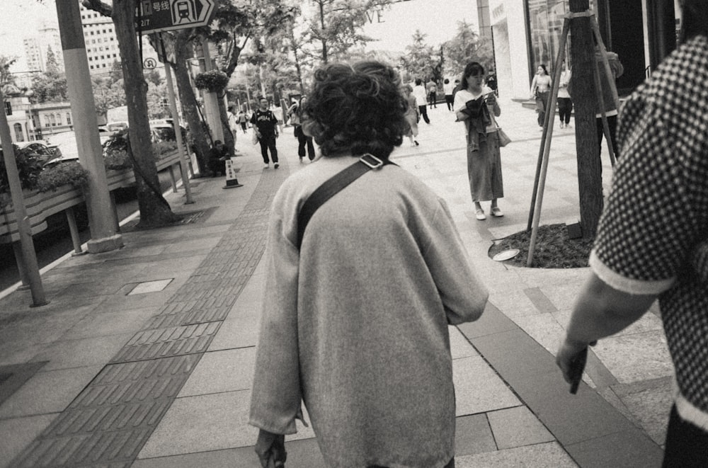 a black and white photo of a woman walking down a sidewalk