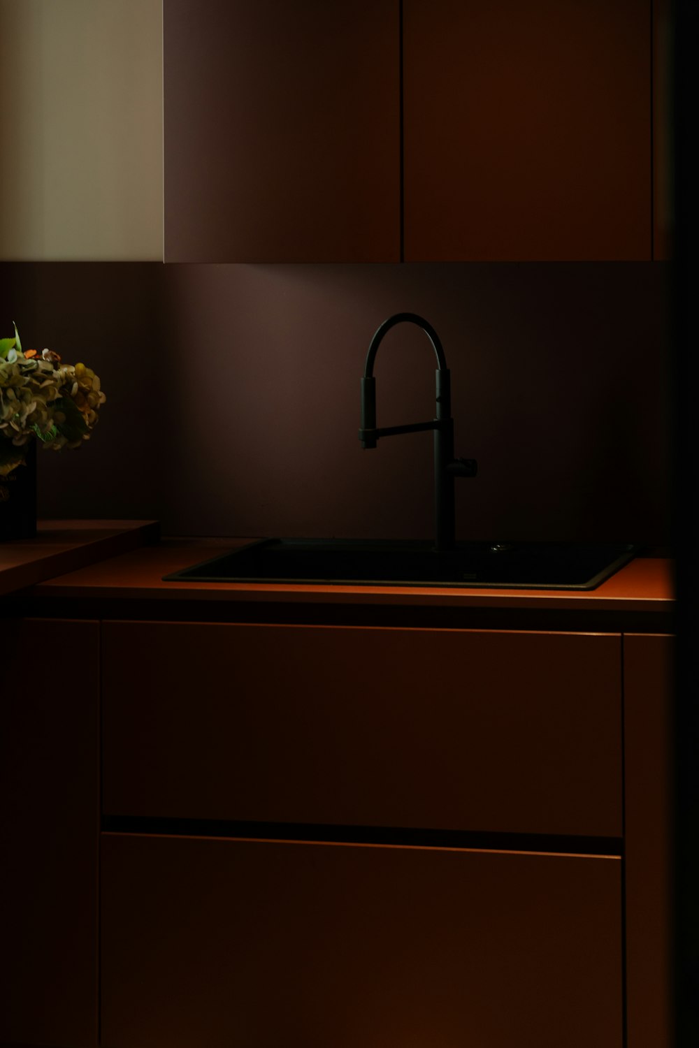 a kitchen with a sink, cabinets and a vase of flowers