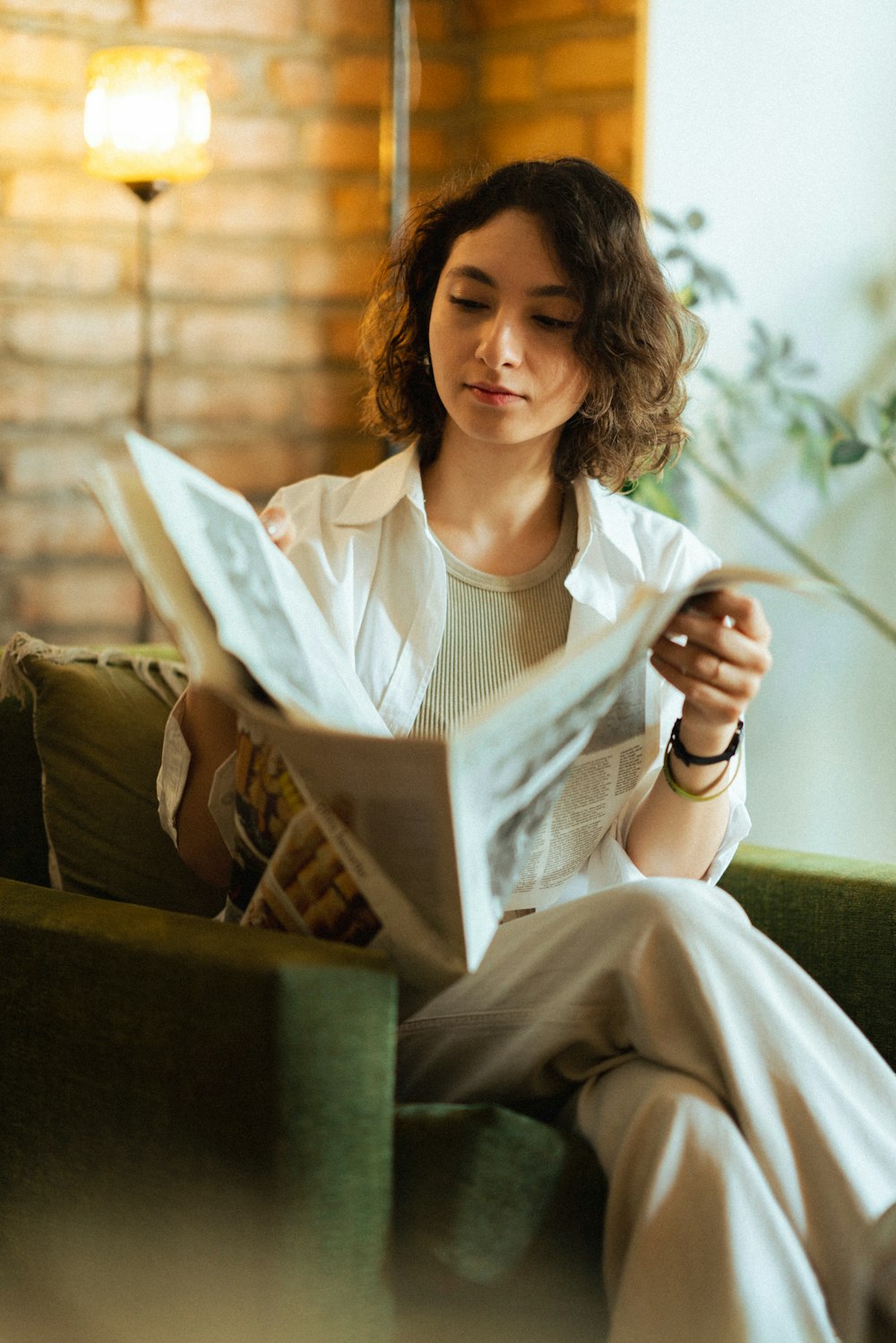 a woman sitting on a couch reading a newspaper