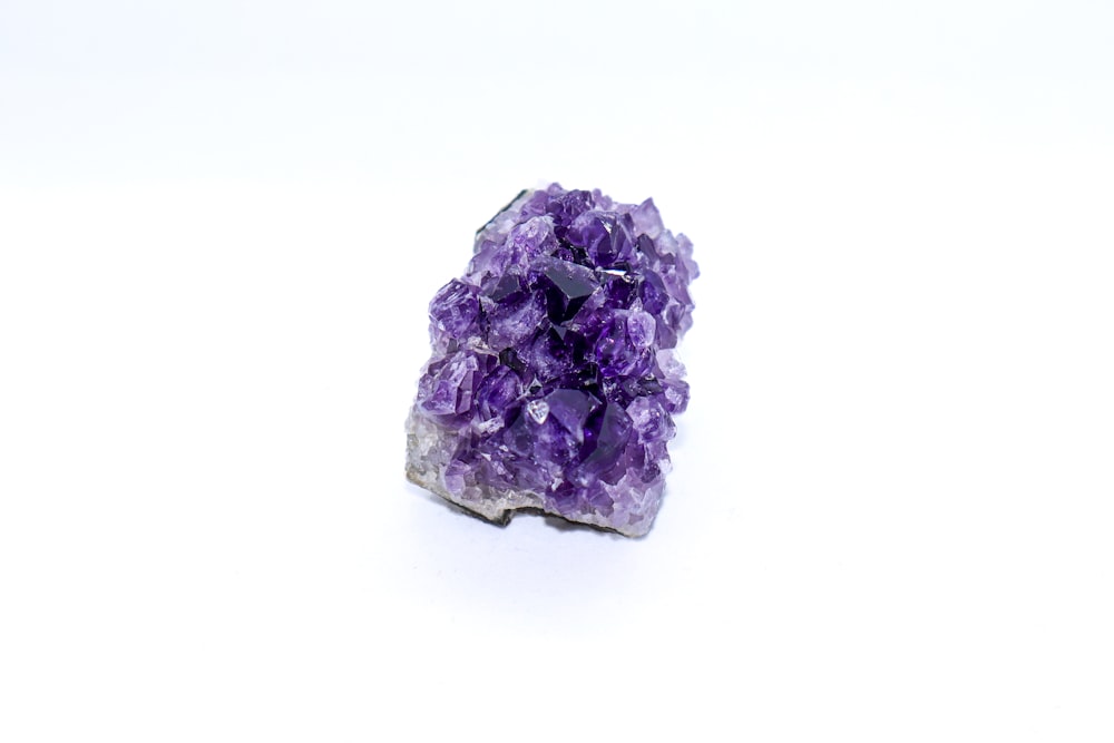 a cluster of purple crystals sitting on top of a white surface
