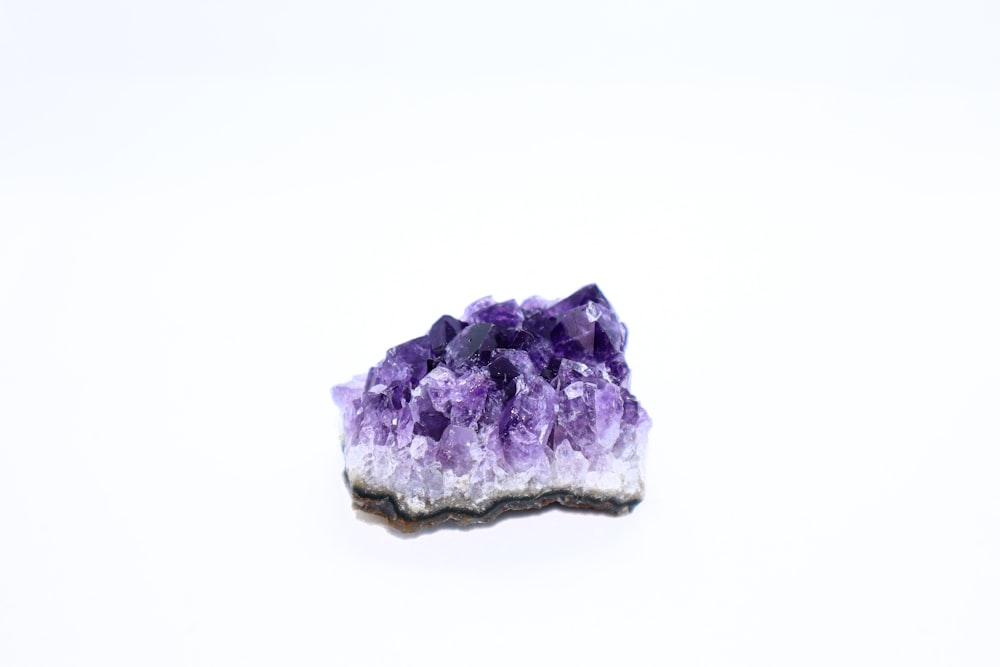a piece of purple and white rock sitting on top of a white surface