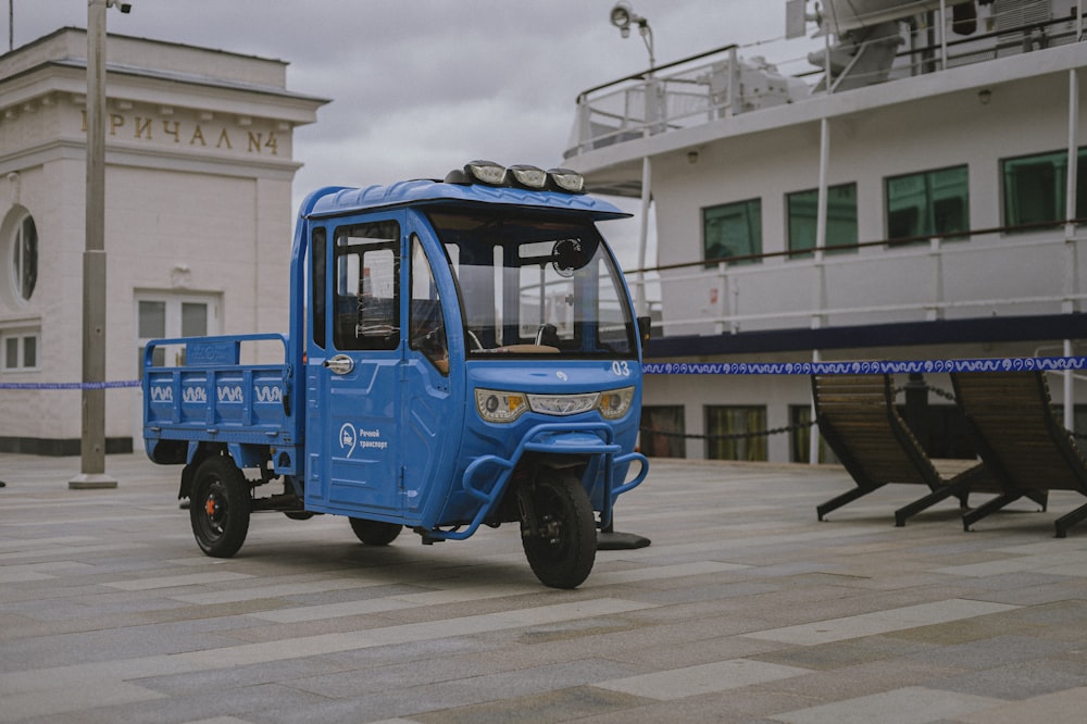 Un pequeño camión azul estacionado frente a un edificio