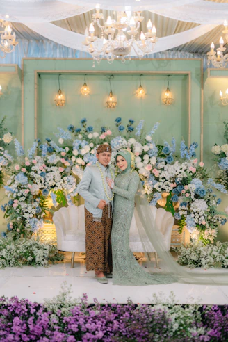 a couple posing for a picture in front of a floral backdrop