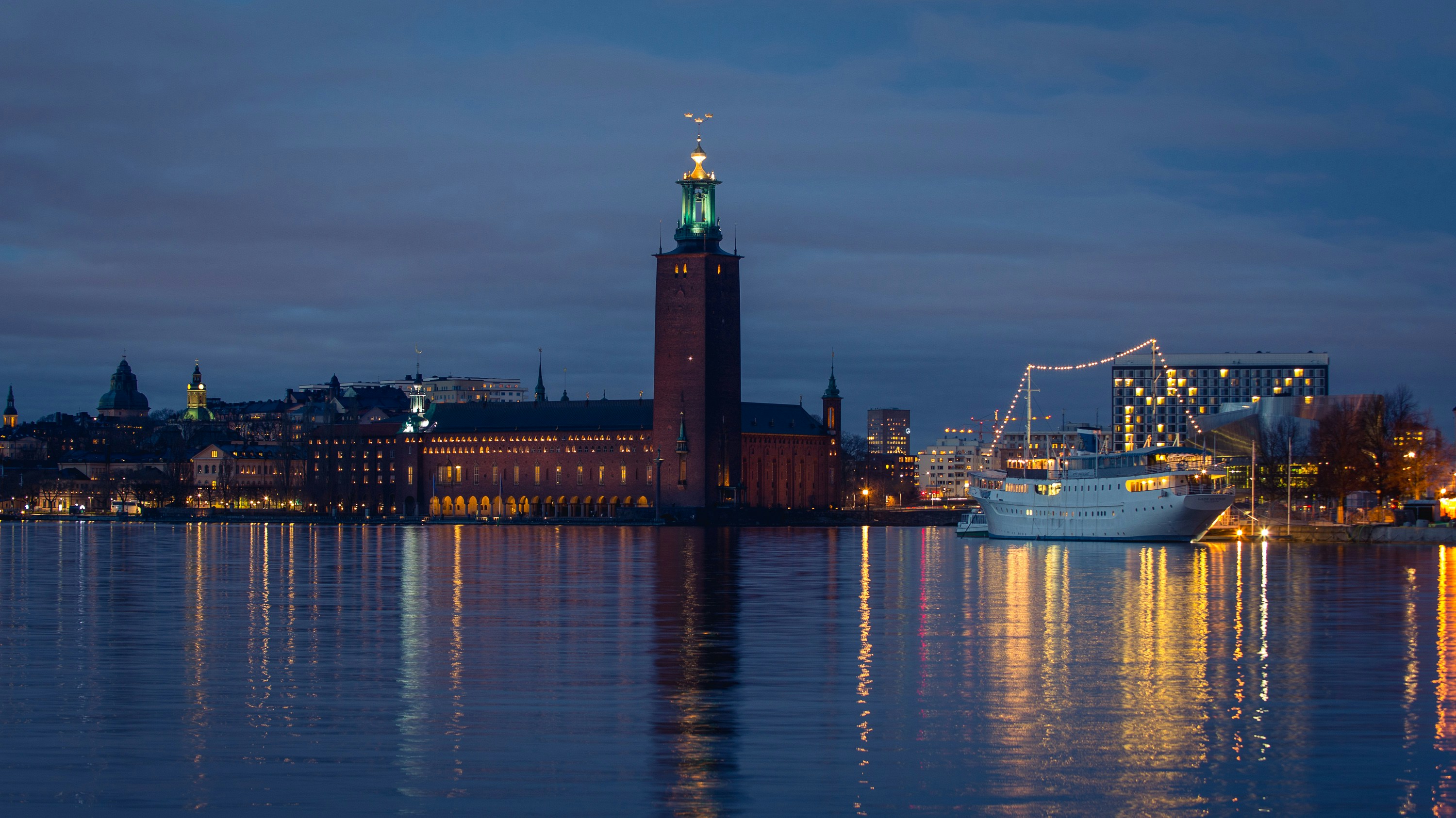 a large building with a clock tower next to a body of water, 
