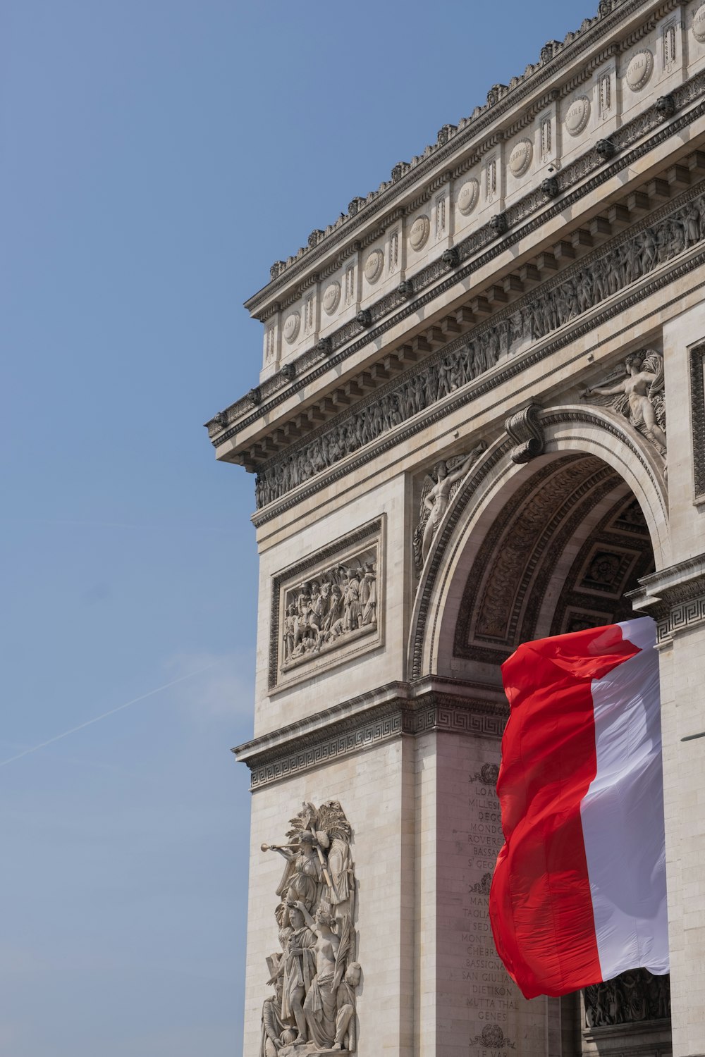 a red white and blue flag is flying in front of the arc de trioe