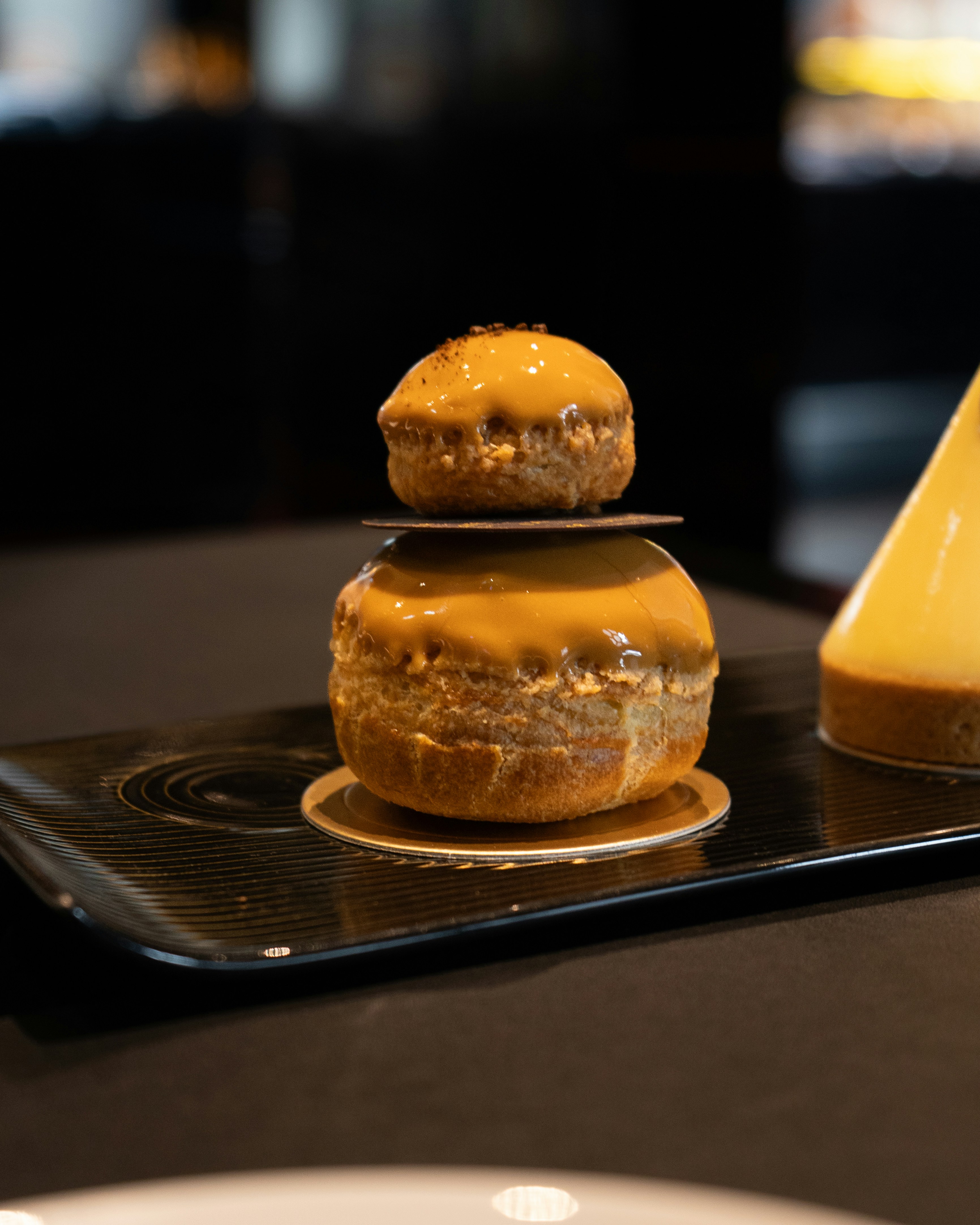 Cream puff choux pastry with caramel drizzle on parchment paper, warm rustic background