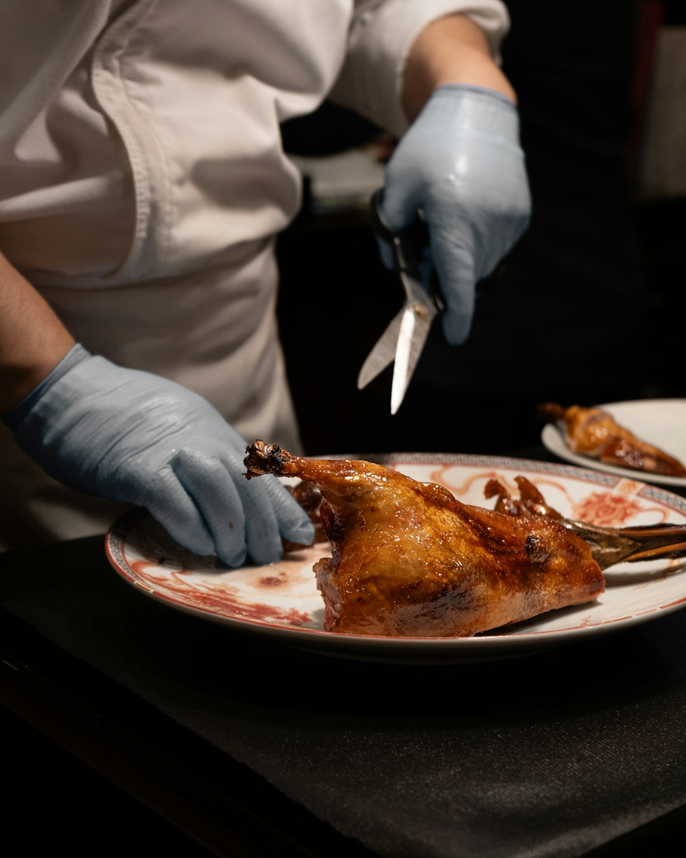 a person in white gloves cutting a piece of meat on a plate