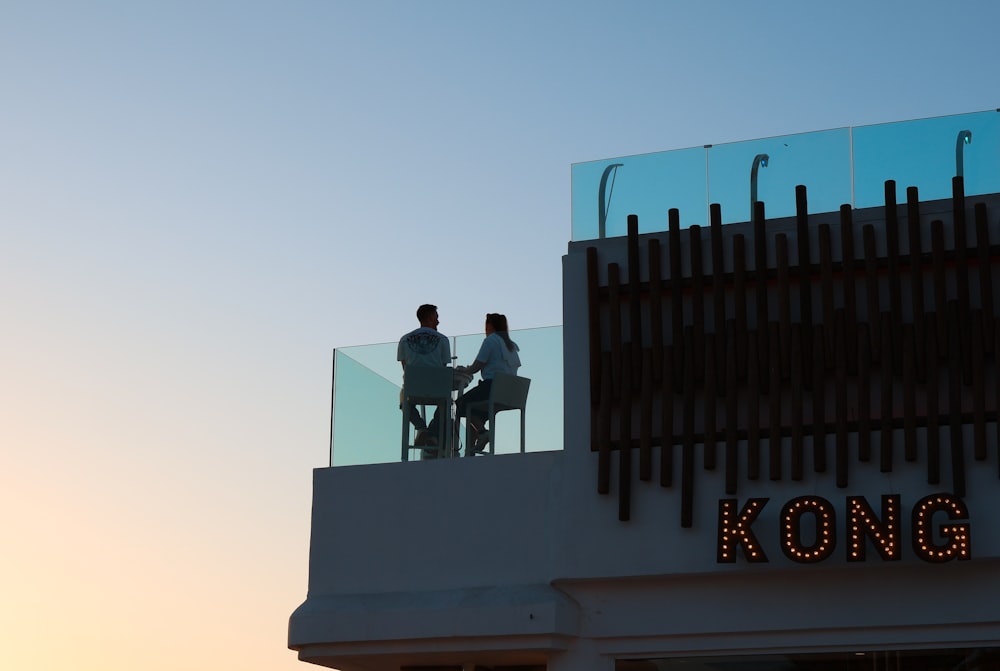 a couple of people sitting on top of a building