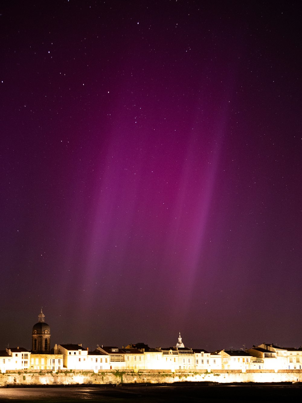 the aurora lights shine brightly in the night sky over a city