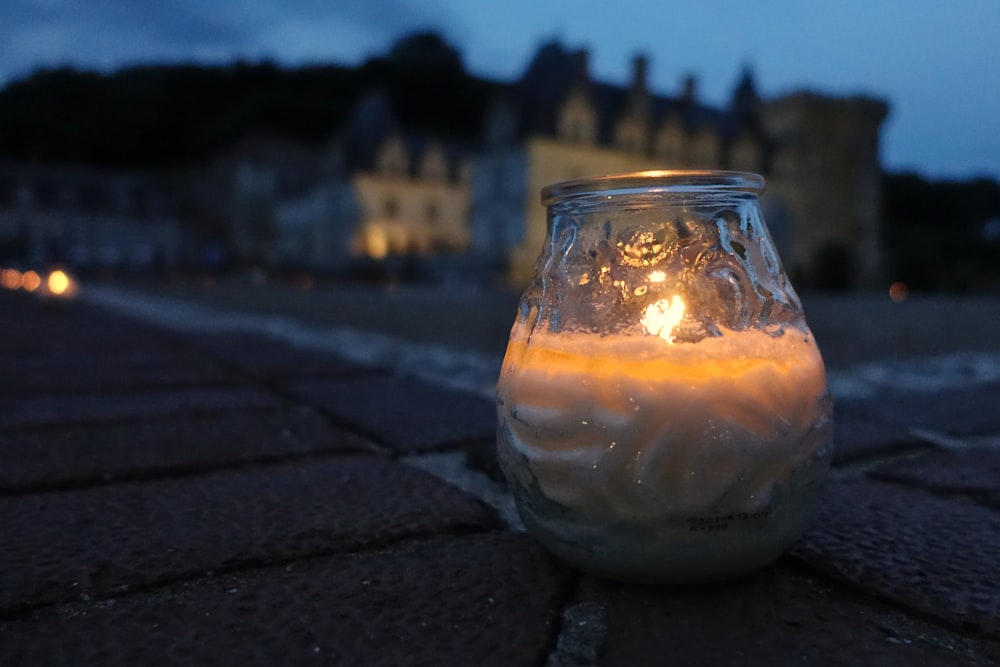 a lit candle sitting on the ground in front of a building